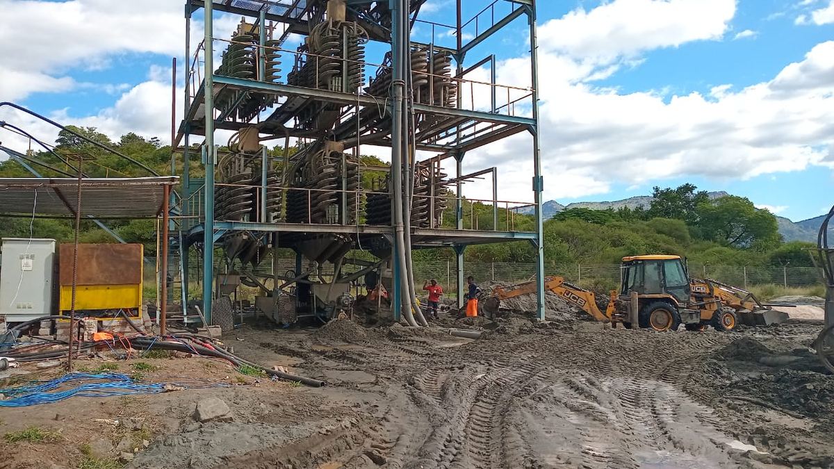 Tractor-loader-backhoe feeding material to a spiral concentrator plant